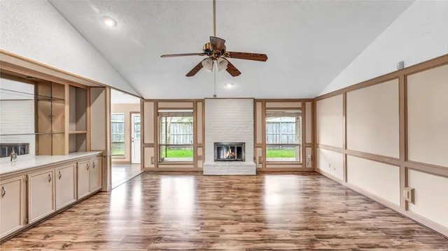 wooden floor in an empty room with a window and a kitchen