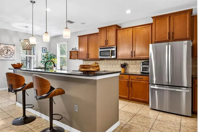 a kitchen with stainless steel appliances granite countertop a refrigerator a stove a sink a dining table and chairs