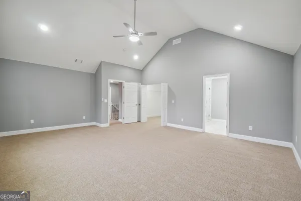 an empty room with an entryway and chandelier fan