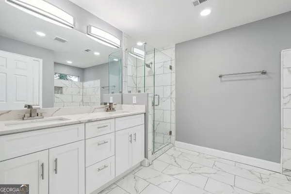 a bathroom with a double vanity sink mirror and shower