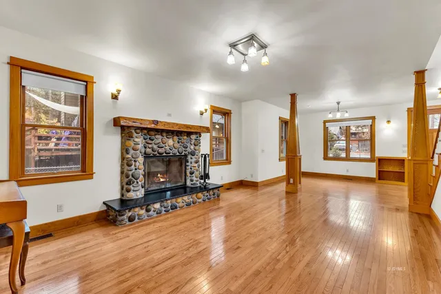 a dining room with wooden floor a chandelier a wooden table and chairs
