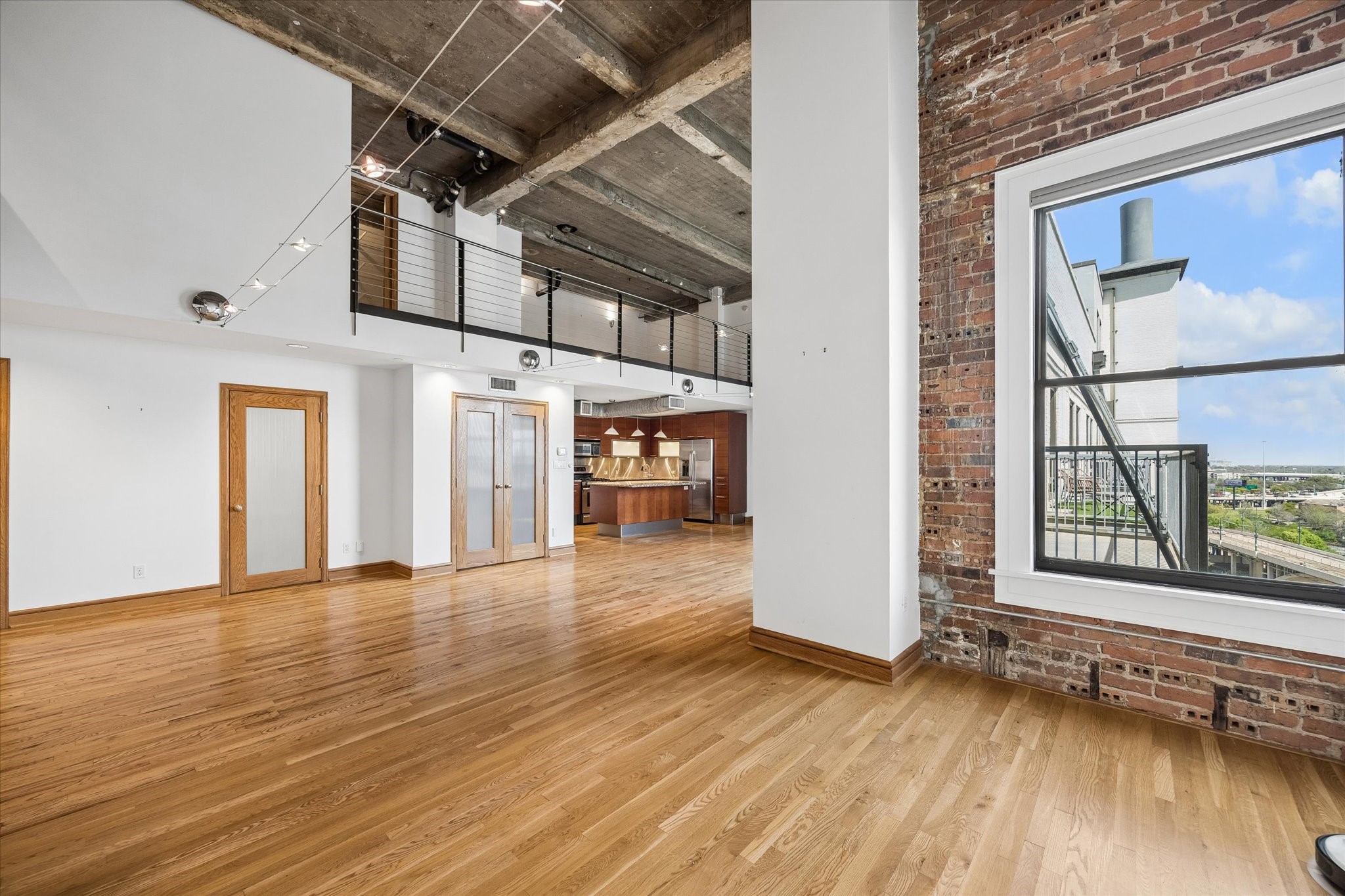 915 Franklin Street, Unit 9L Houston, TX 77002 - Photo 3 of 50 Stunning high-ceiling condo featuring exposed brick, oversized windows, and an open-concept living area.
