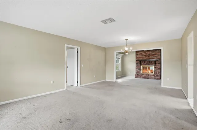 a view of an empty room with window and chandelier