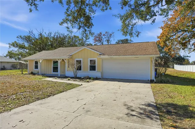 a view of a white house with a yard and large tree