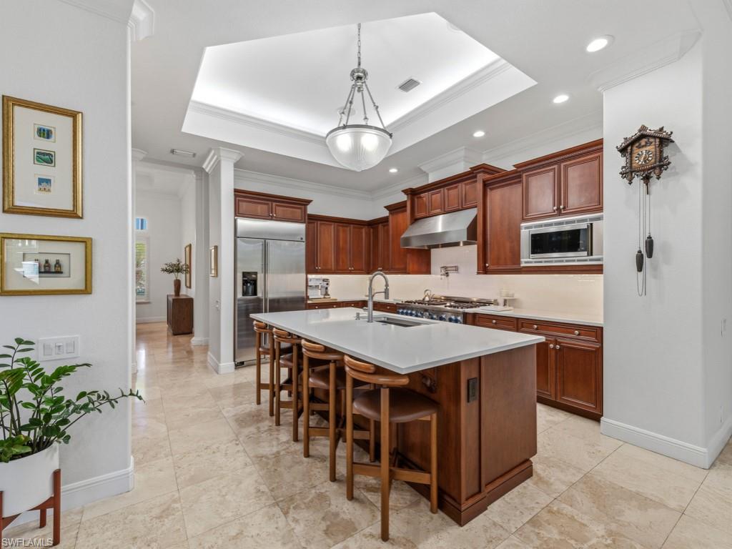 506 Ridge Drive Naples, FL 34108 - Photo 17 of 33 Kitchen with a kitchen breakfast bar, a tray ceiling, built in appliances, hanging light fixtures, and a center island with sink