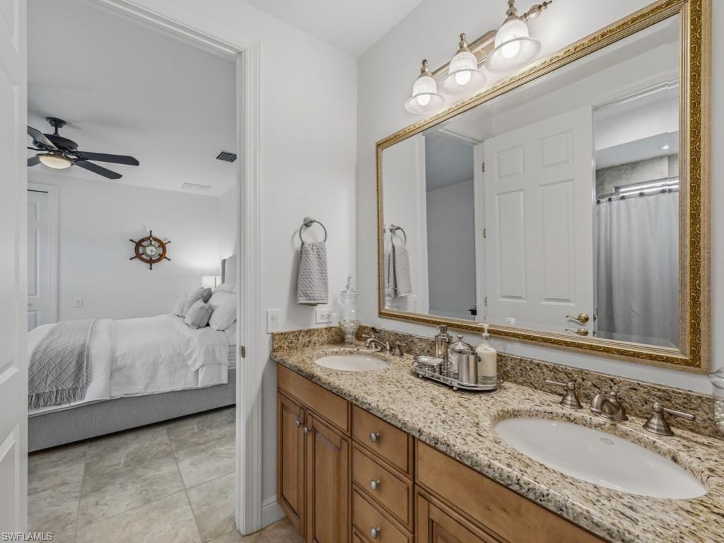 506 Ridge Drive Naples, FL 34108 - Photo 30 of 33 Ensuite bathroom featuring double vanity, curtained shower, and a ceiling fan