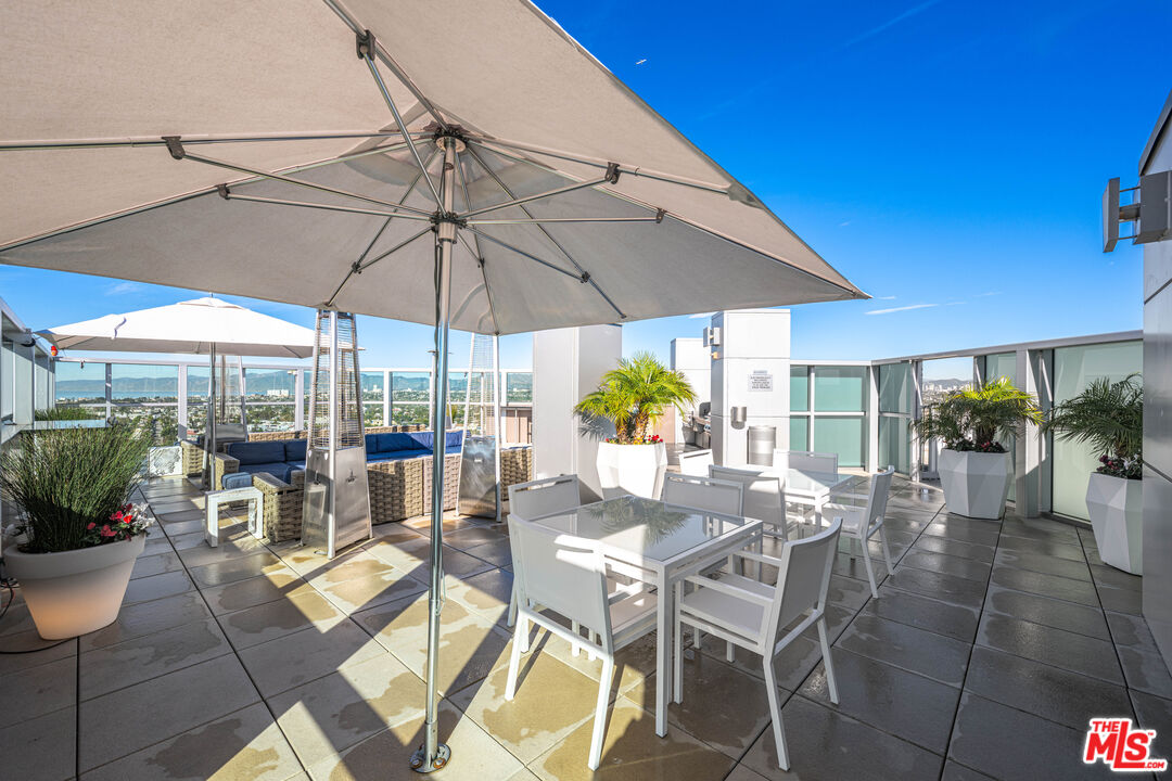 13700 Marina Pointe Drive, Unit 1007 Marina del Rey, CA 90292 - Photo 31 of 53 a view of a patio with a dining table and chairs under an umbrella