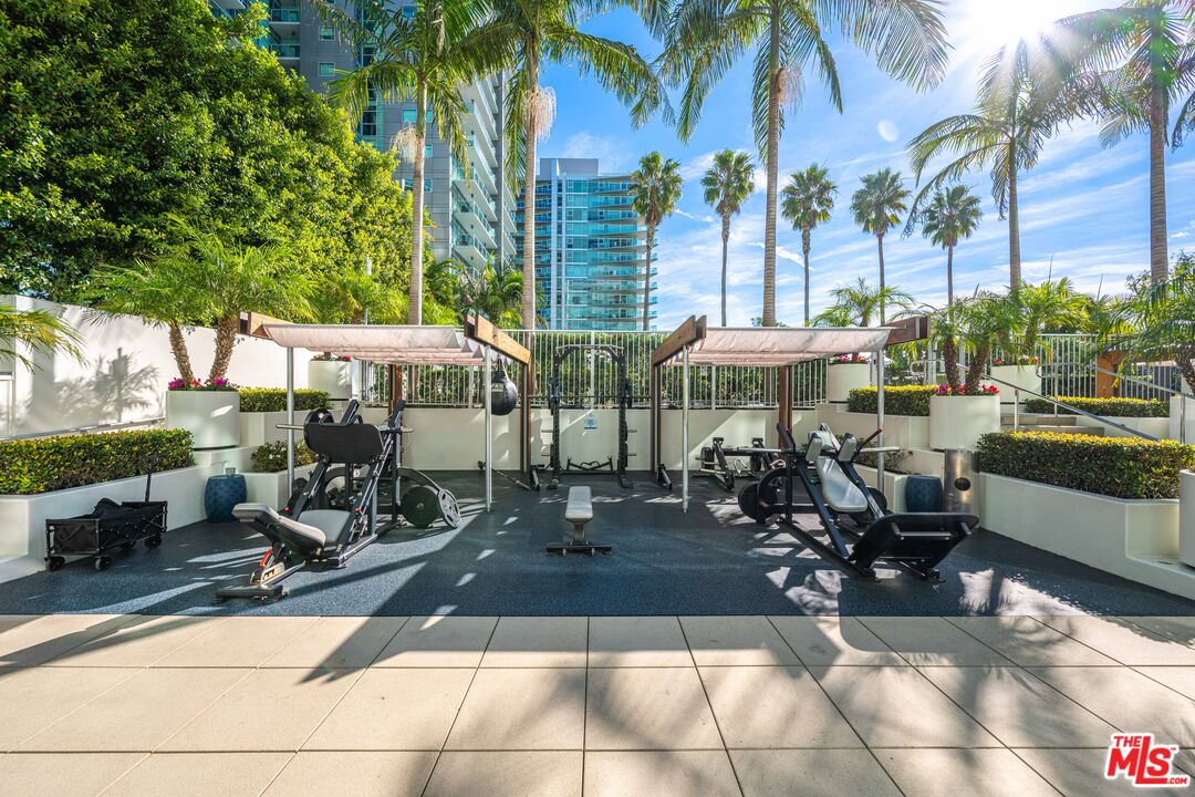 13700 Marina Pointe Drive, Unit 1007 Marina del Rey, CA 90292 - Photo 39 of 53 a view of a patio with table and chairs potted plants and palm trees