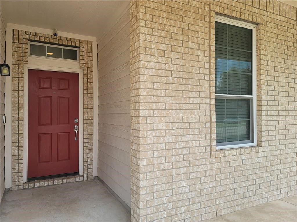 208 Hummingbird Lane Leander, TX 78641 - Photo 3 of 25 A welcoming front entrance showcases a classic brick facade and a vibrant red door.