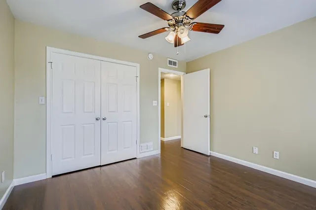 an empty room with wooden floor a ceiling fan and closet