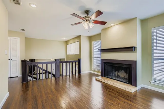 a view of a livingroom with fireplace wooden floor and a ceiling fan
