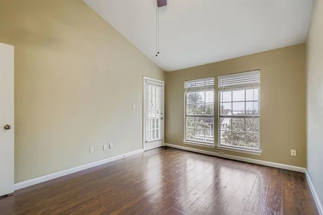 an empty room with wooden floor and windows