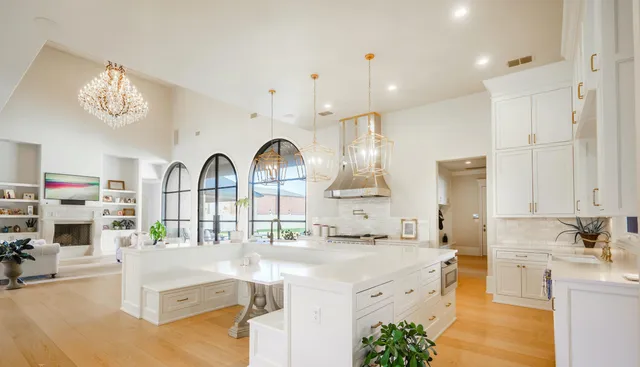 a large white kitchen with lots of counter space a sink and living room view