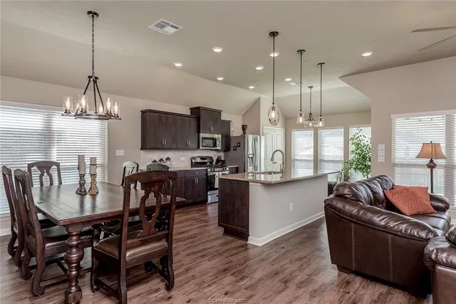 a living room with stainless steel appliances kitchen island granite countertop furniture and a wooden floor