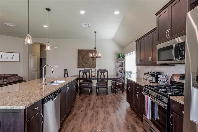 a kitchen with granite countertop a sink a counter space stainless steel appliances and cabinets