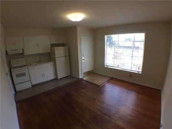 an empty room with wooden floor cabinet and windows