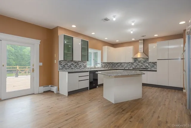 a large kitchen with a large counter top a sink stainless steel appliances and cabinets