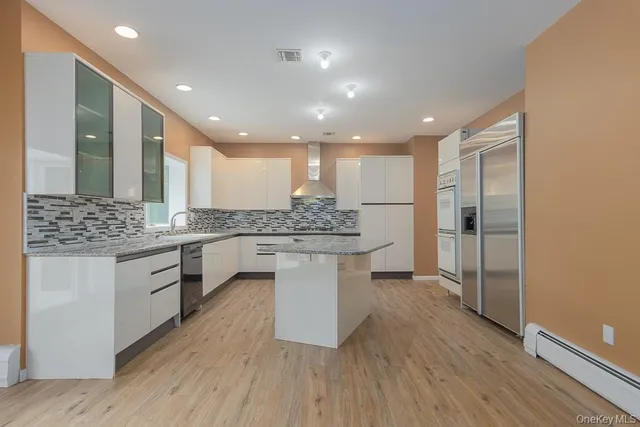 a large kitchen with a sink and white cabinets