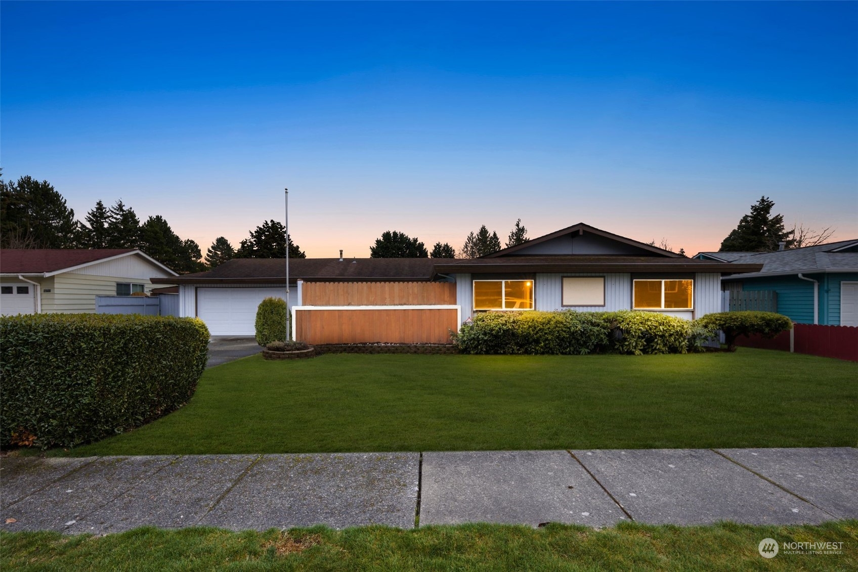 a front view of a house with a garden and lake
