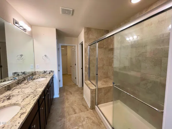a spacious bathroom with a granite countertop double vanity sink a mirror and a bathtub