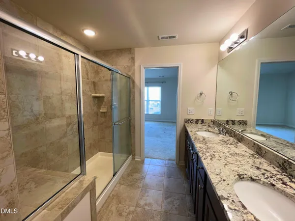 a bathroom with a granite countertop sink a mirror and shower