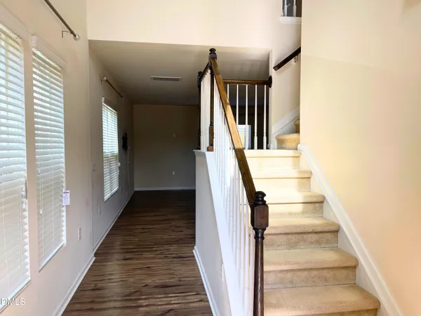 a view of staircase with wooden floor and lots of frames on wall