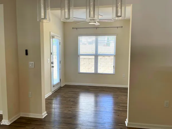 an empty room with wooden floor closet and windows