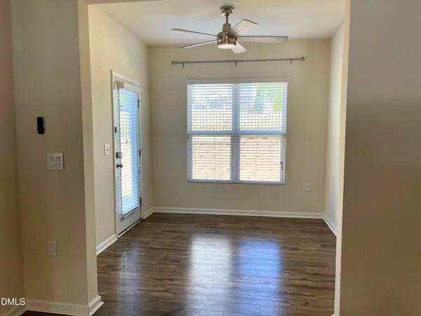 a view of an empty room with wooden floor and a window