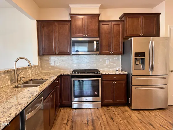 a kitchen with granite countertop a refrigerator stove and microwave