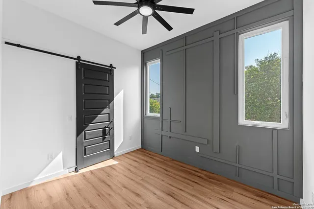 a view of empty room with wooden floor and fan