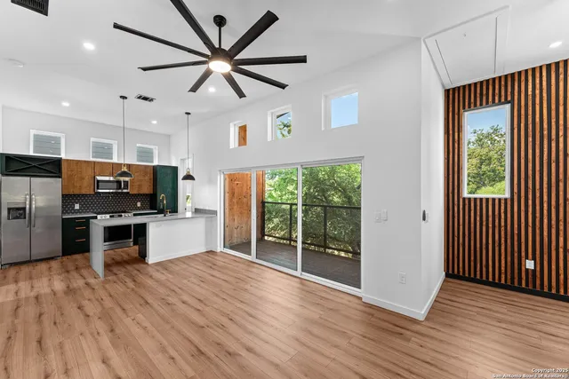 a open kitchen with stainless steel appliances wooden floor and a large window