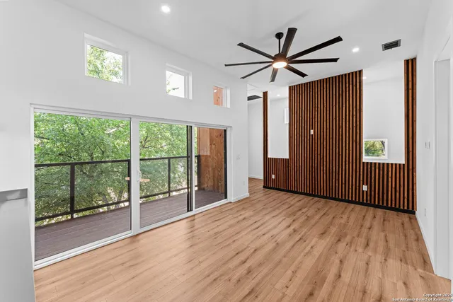 a view of a livingroom with wooden floor a ceiling fan and windows