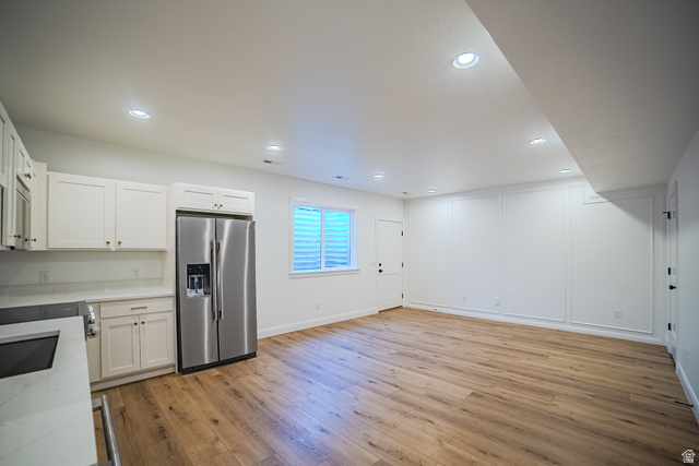 45 North Scarlet Maple Road, Unit 4317 Vineyard, UT 84059 - Photo 31 of 35 Open-concept living space featuring wood-finish flooring, recessed lighting, and a kitchen area with white cabinetry, a stainless steel refrigerator, and light-toned countertops