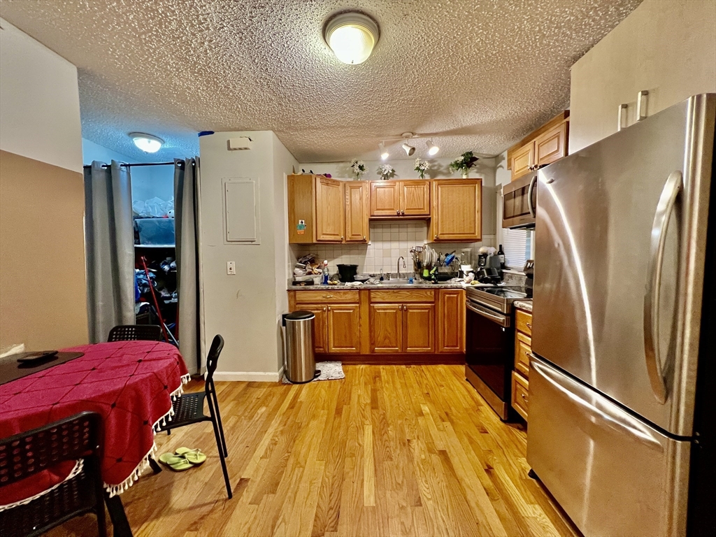 227 Everett Street, Unit 4 Boston, MA 02128 - Photo 3 of 7 a kitchen with stainless steel appliances a refrigerator a stove a sink dishwasher with a dining table and chairs