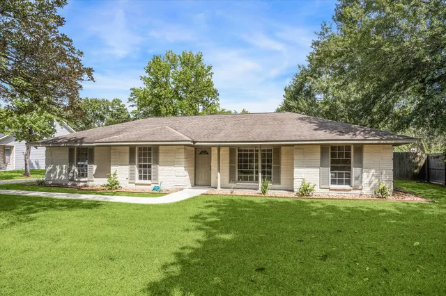 a front view of a house with garden and trees