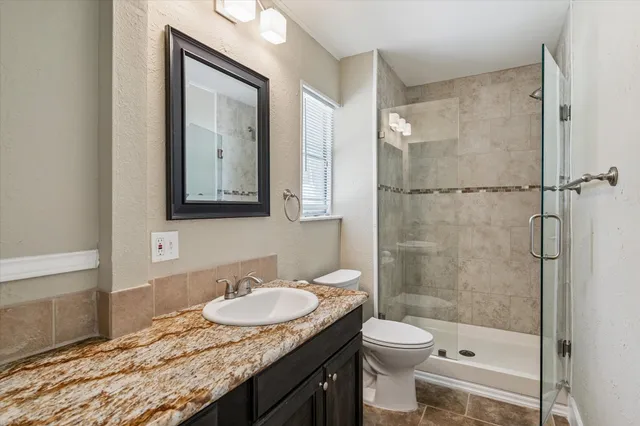 a bathroom with a granite countertop sink toilet and shower