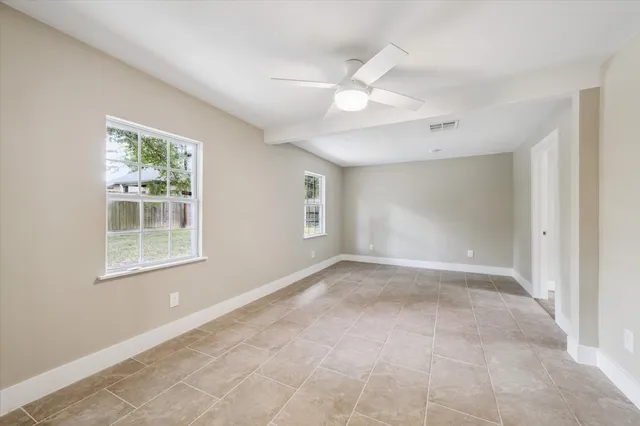 an empty room with windows and fan