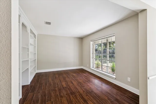 an empty room with wooden floor and windows