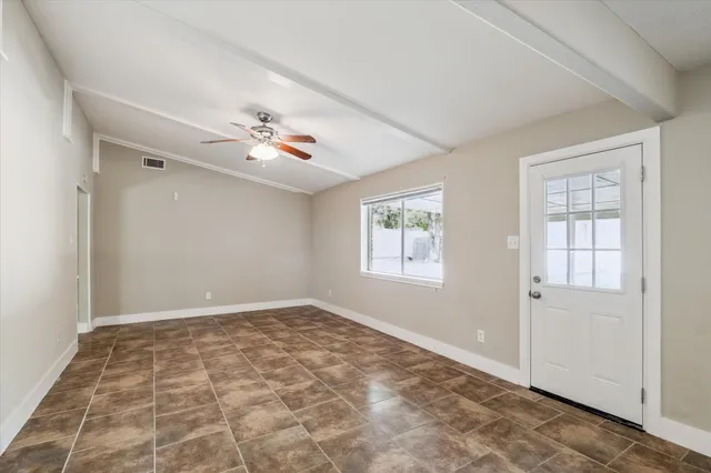 an empty room with windows and ceiling fan
