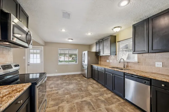 a kitchen with stainless steel appliances granite countertop a sink stove and cabinets