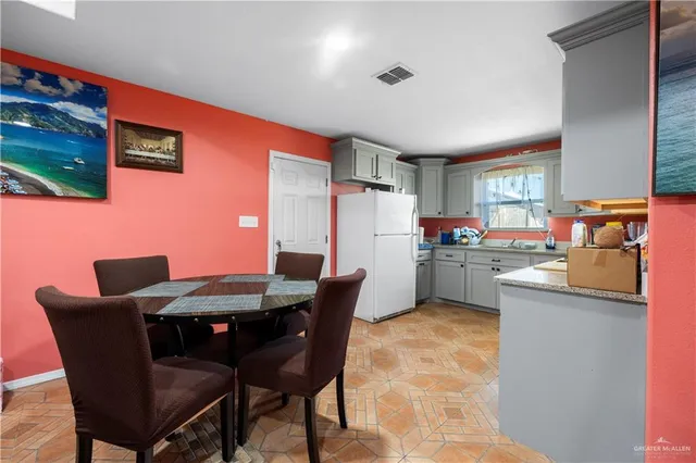 a kitchen with a dining table chairs and refrigerator