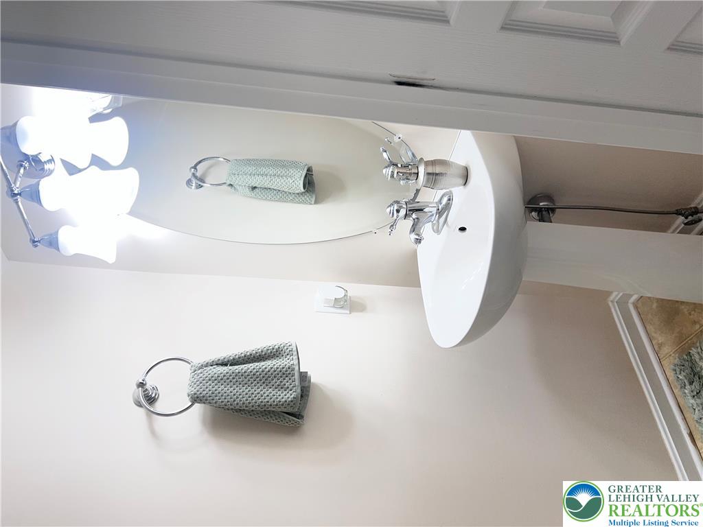 8549 Gateway Road Breinigsville, PA 18031 - Photo 17 of 26 A well-lit powder room features a modern pedestal sink and elegant wall-mounted lighting.