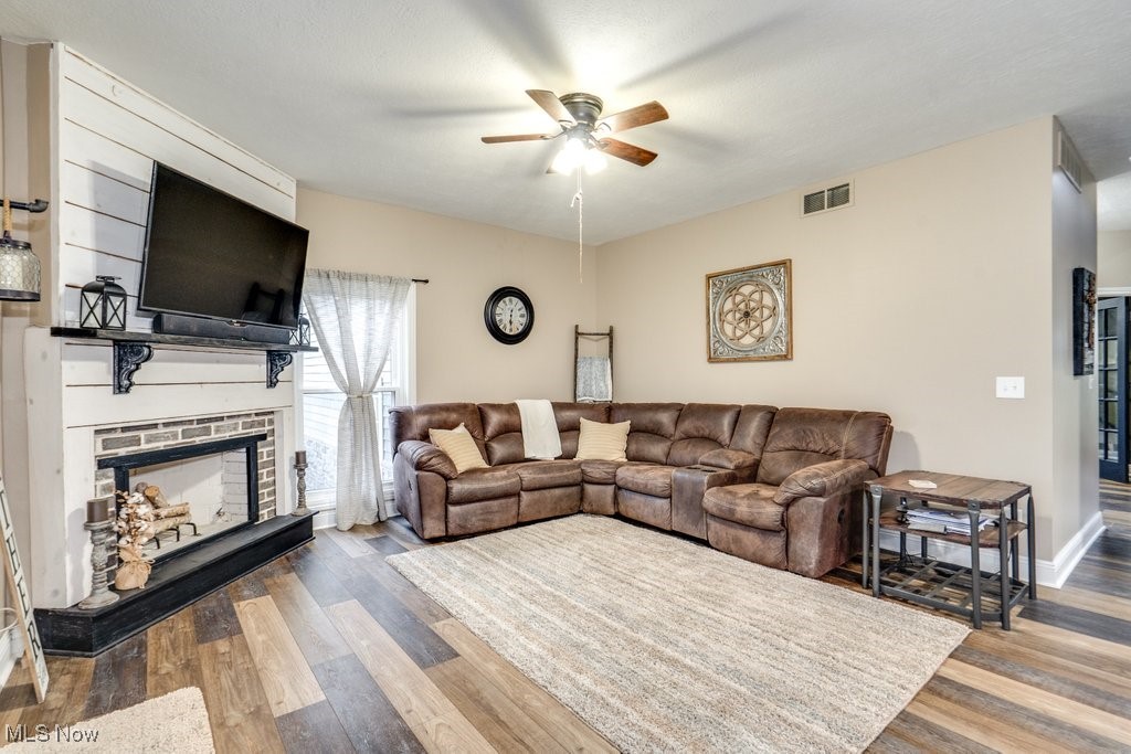 4121 New Milford Road Rootstown, OH 44272 - Photo 12 of 50 Living area featuring a fireplace, visible vents, a ceiling fan, and wood finished floors