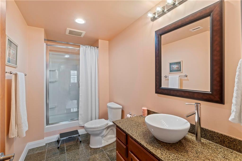 306 Fourth Avenue, Unit 1203 Pittsburgh, PA 15222 - Photo 27 of 40 a bathroom with a granite countertop toilet a sink and a mirror