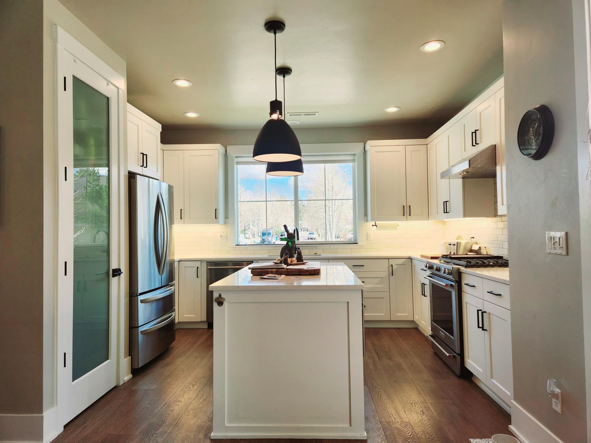 Beautiful kitchen with quartz countertops, tile backsplash, lots of cabinets, wood floors and stainless steal appliances.