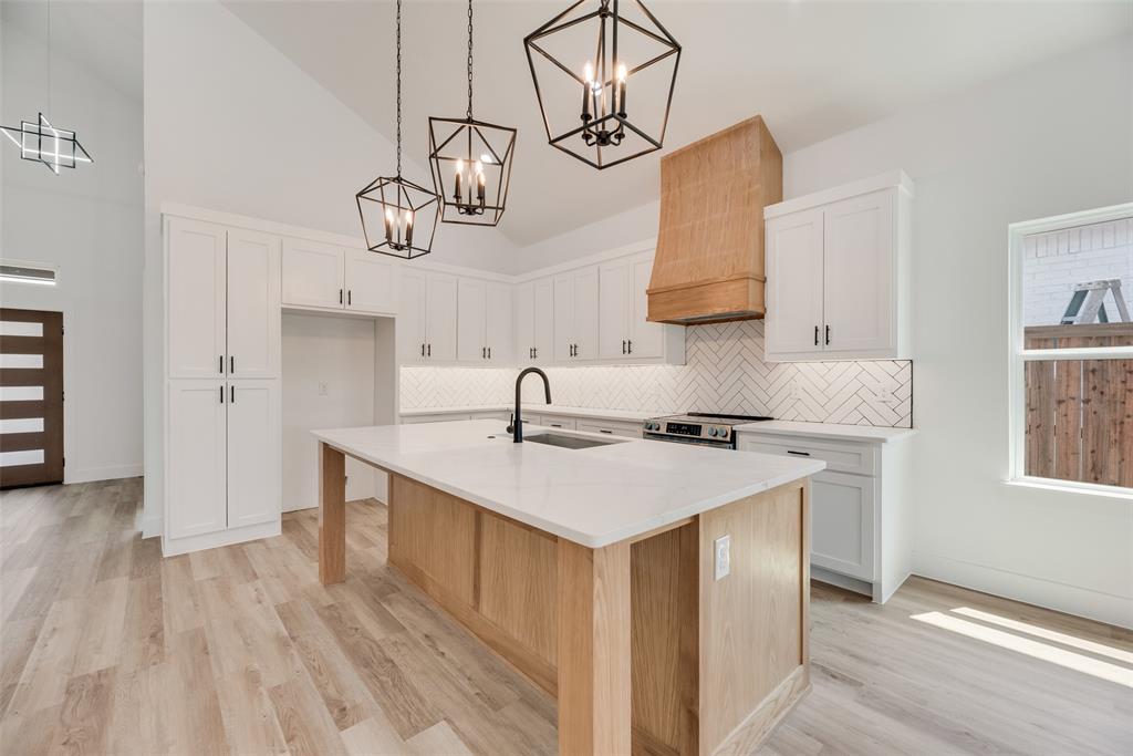 a kitchen with a sink dishwasher a stove and white cabinets with wooden floor