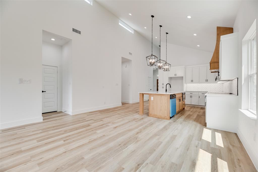 110 Hesed Street Greenville, TX 75402 - Photo 7 of 33 a view of a kitchen with kitchen island a sink wooden floor and a chandelier