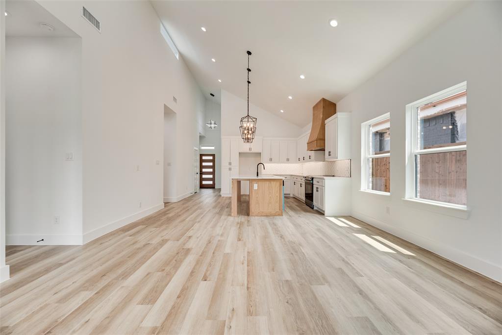 110 Hesed Street Greenville, TX 75402 - Photo 9 of 33 a large white kitchen with kitchen island a stove a sink dishwasher and white cabinets with wooden floor