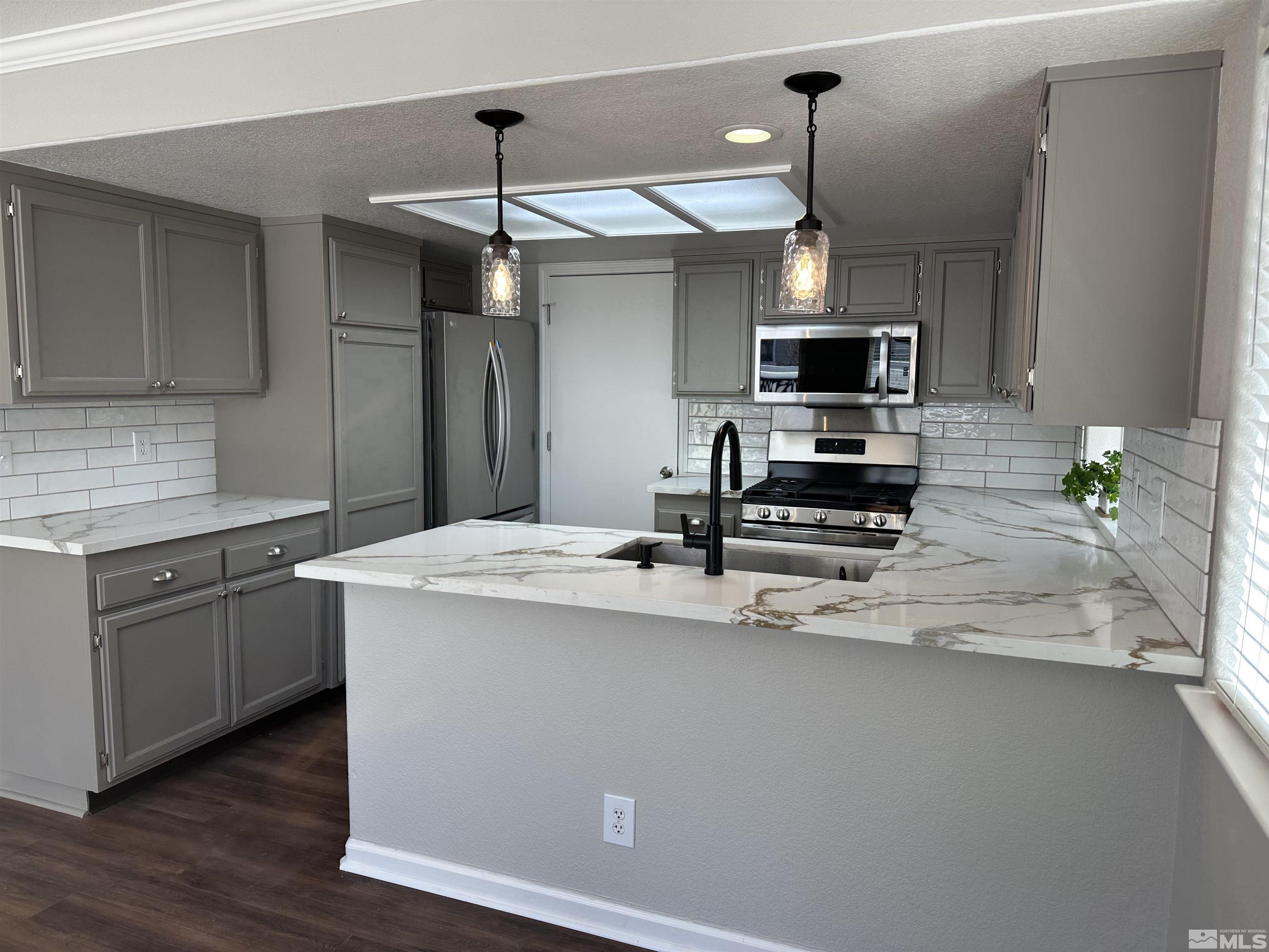 7485 Wheeldale Circle Reno, NV 89511 - Photo 3 of 12 a kitchen with kitchen island white cabinets and stainless steel appliances