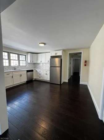 a kitchen with a refrigerator stove and wooden floor